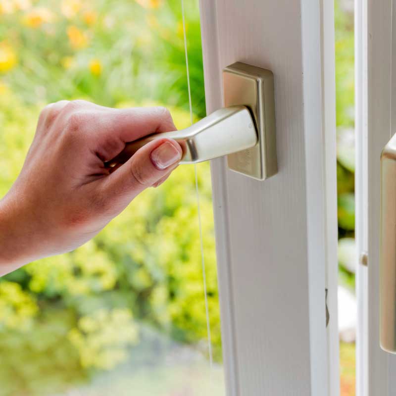 Eine Hand öffnet ein Fenster.